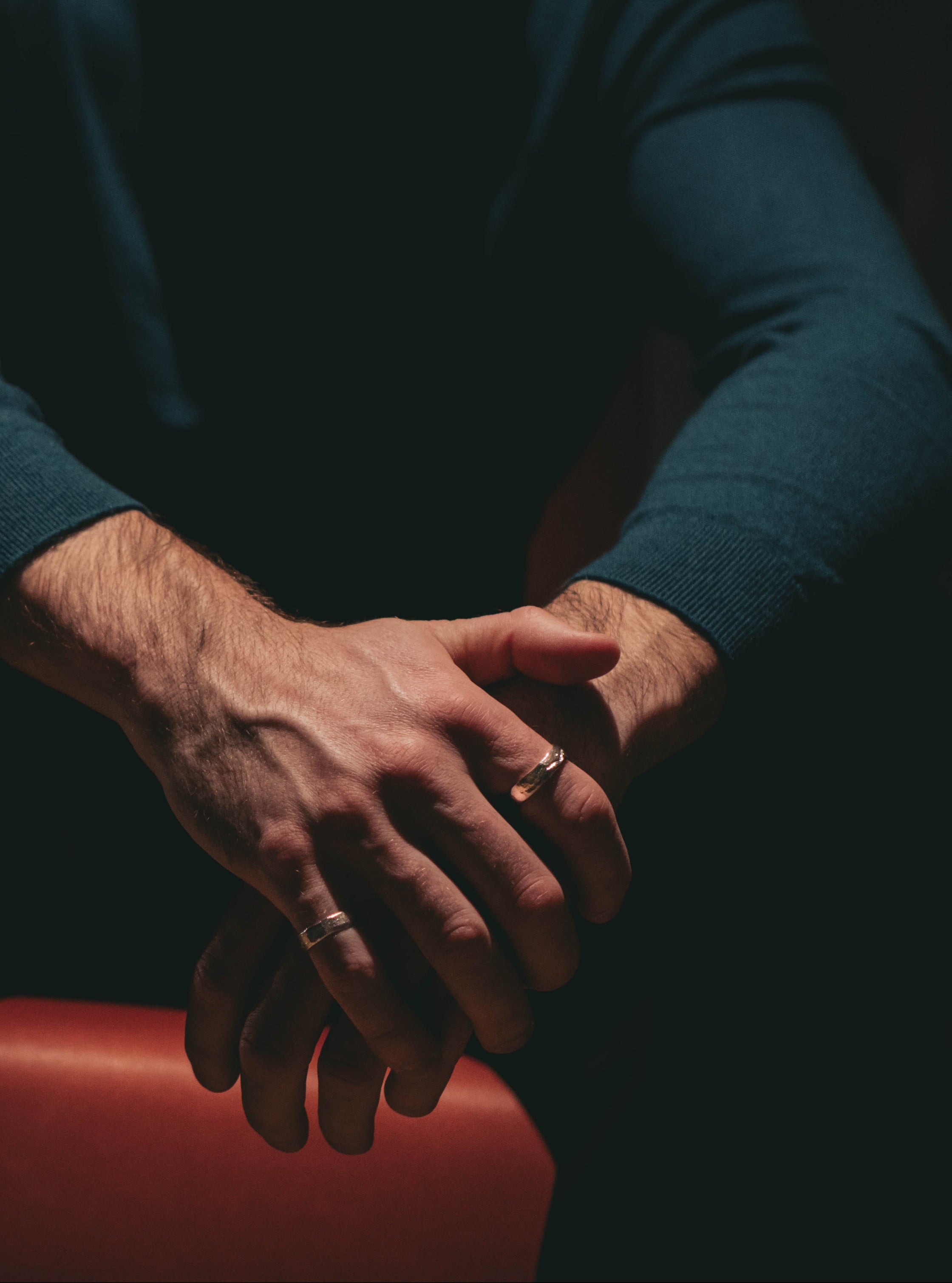 Close-up of a person's hands with rings on a dark background
